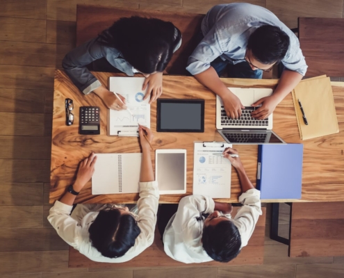 A project manager and a client collaborating on a successful LMS implementation plan shown on a laptop screen.